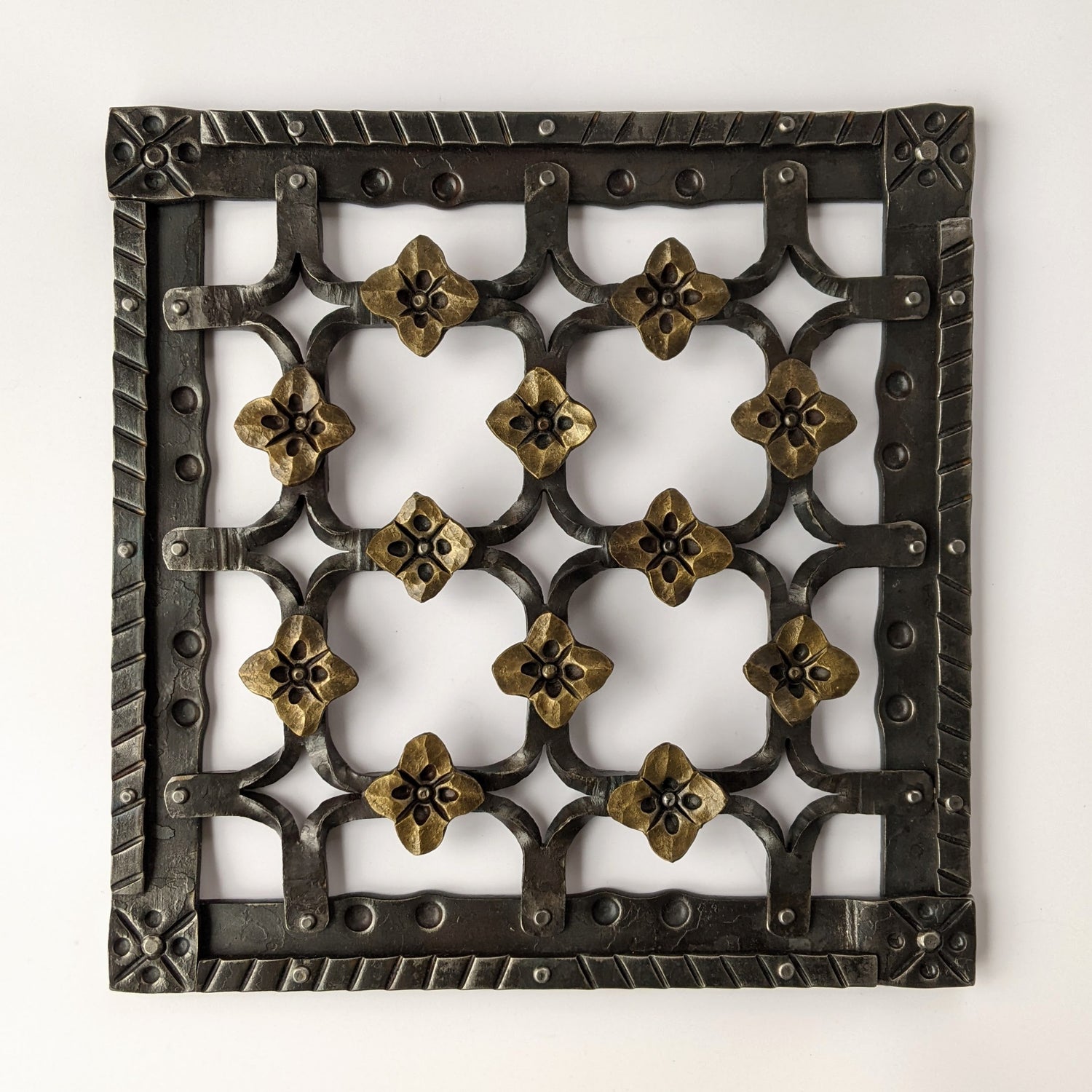 Hand forged wall art, decorated with heavy texture, flowers and diamond shapes.
